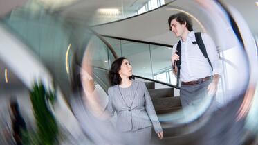 Two students in stairwell at Sands Family Grounds with abstract swirl overlaid